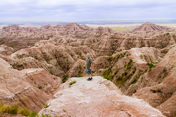 tourest stands on rock looking out onto deep gorges Badlands South Dakota view image